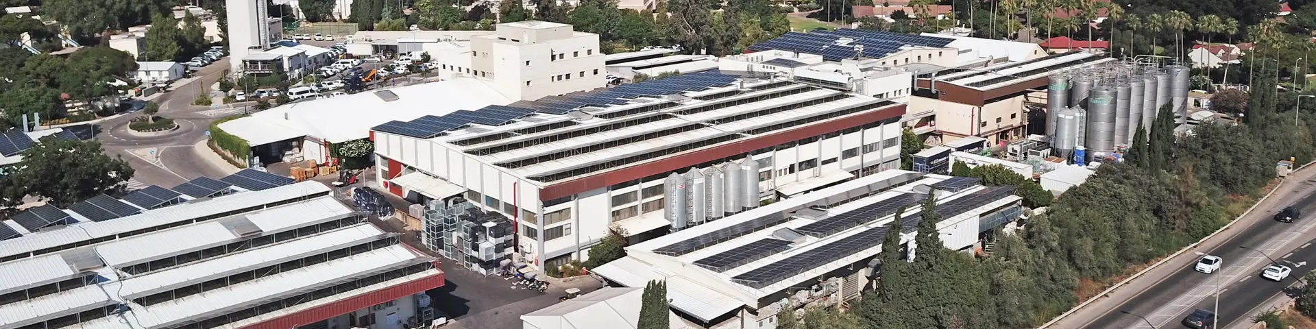 Aerial view of Tama’s modern manufacturing facility in Israel, featuring industrial production buildings with rooftop solar panels, storage silos, and advanced agricultural packaging operations.